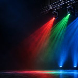 Red, green, and blue stage laser beams projected above an empty performance stage.