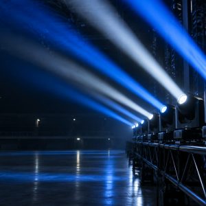 LED beam moving head fixtures casting narrow blue and white beams across a dark stage.
