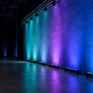 Linear LED wall wash fixtures creating a smooth teal, violet, and blue wall wash.