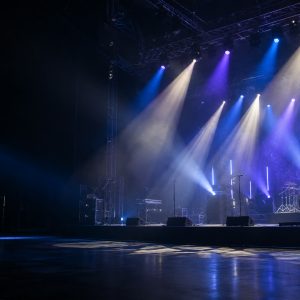 Concert stage illuminated by blue, violet, and white stage lights.